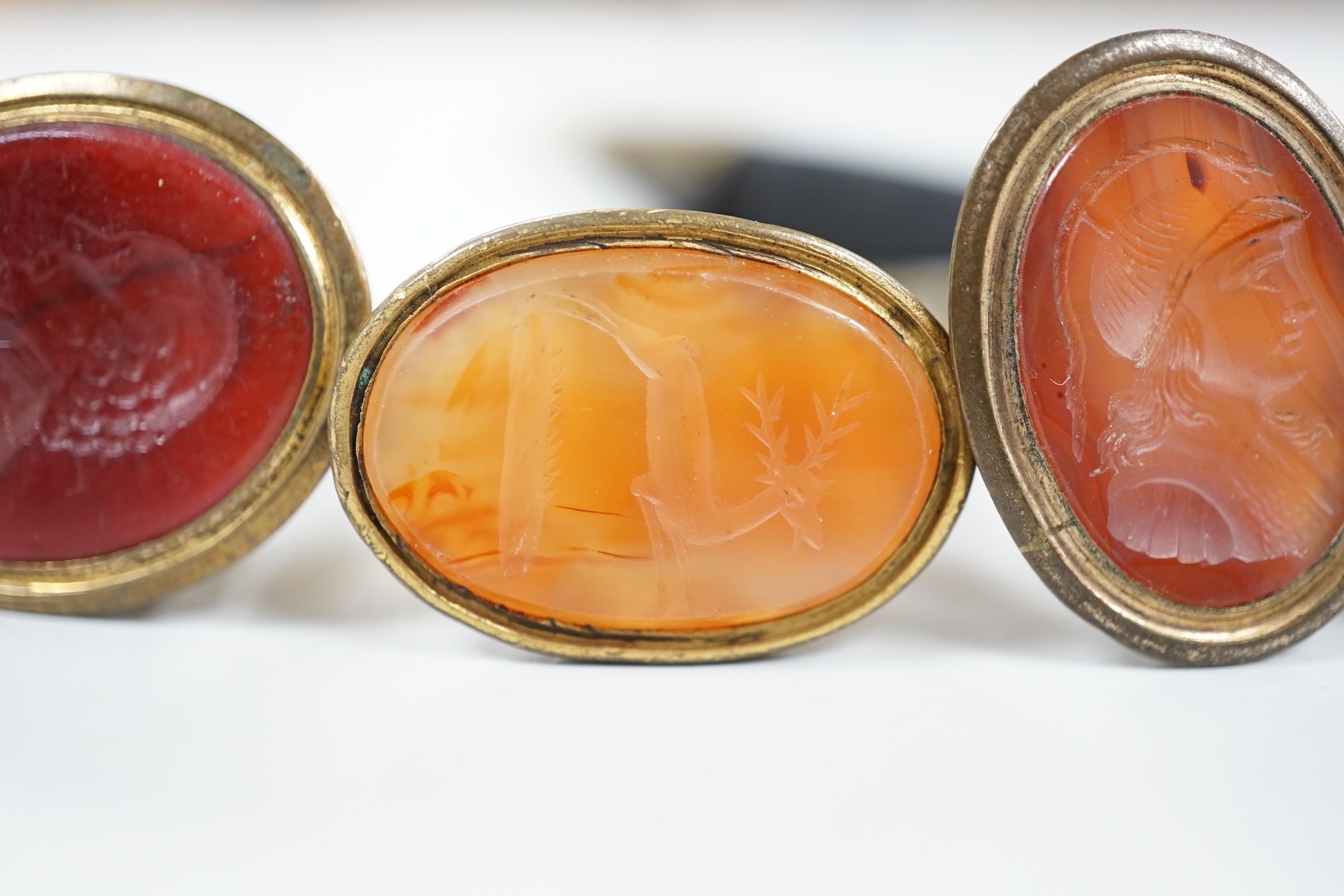 Four assorted 19th century gold plated and agate or hardstone set oval fob seals, largest 37mm, two matrices carved with busts and two with animals.